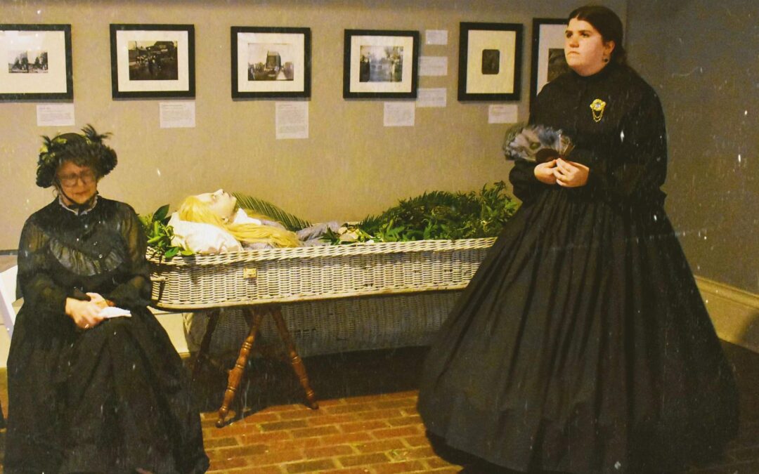 Two women in black period dresses from the 1800s.
